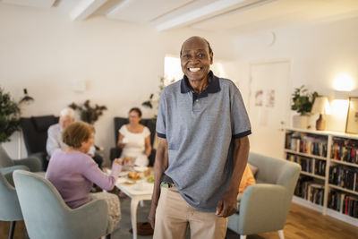 Portrait of happy senior man standing at retirement home