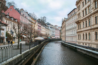 Canal amidst buildings in city against sky