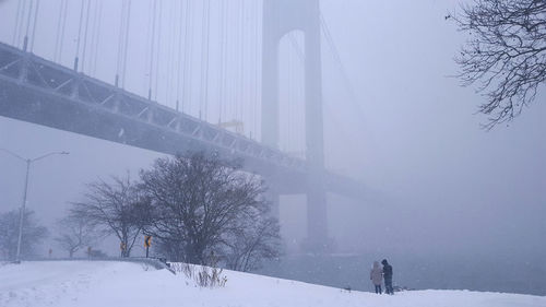 People standing on snow by the river