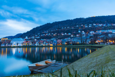 Reflection of houses and mountains in lake against sky