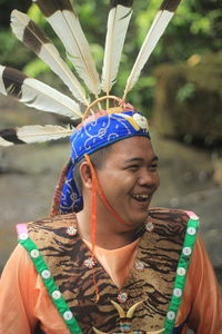 Happy man wearing traditional clothing looking away while standing in forest