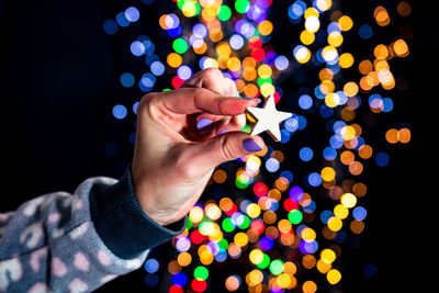 Midsection of person holding illuminated christmas lights at night