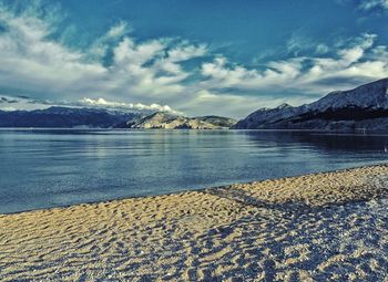 Scenic view of lake by snowcapped mountains against sky