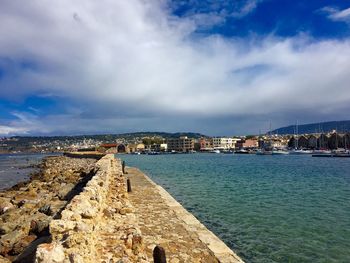 Footpath amidst sea against cloudy sky