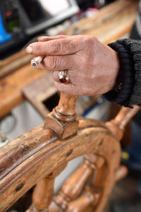 Cropped hand of man smoking cigarette while holding helm in boat