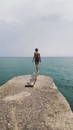 Young woman looking at sea against sky