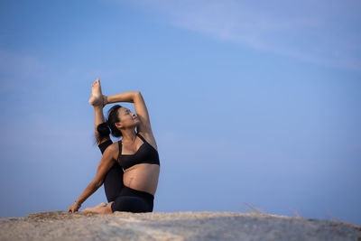 Full length of woman wearing sunglasses against blue sky