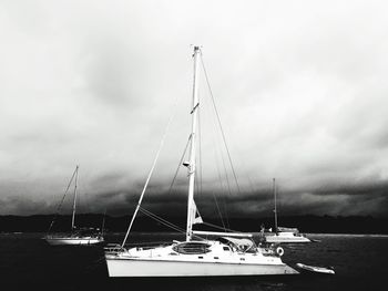 Boats in harbor against cloudy sky