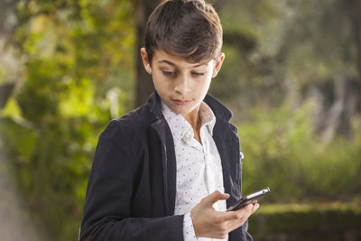 Thoughtful teenage boy holding mobile phone