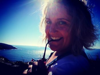 Portrait of smiling young woman by sea against sky