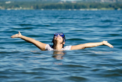 Woman wearing scuba mask in sea with arms outstretched