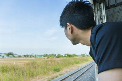 Side view of young man looking through train window
