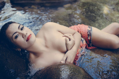 Portrait of young woman lying in river