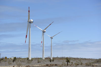 Wind turbines on land against sky