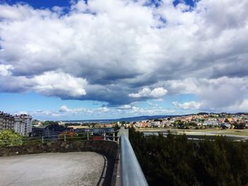 Road by cityscape against sky