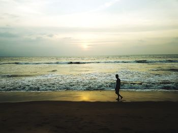 Man standing on beach against sky during sunset