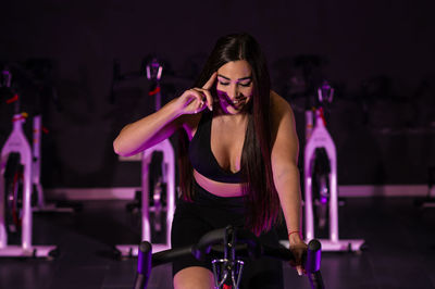 A pretty caucasian woman doing sports with a bicycle in the gym