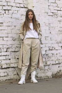 Portrait of teenage girl standing against brick wall