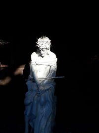 Statue against illuminated lights