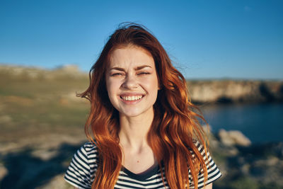 Portrait of smiling young woman against sky