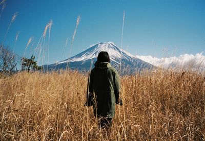 Rear view of man standing on field against clear sky