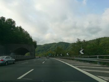 Road by trees against sky