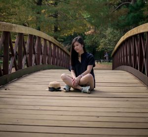 Portrait of young woman sitting on footbridge