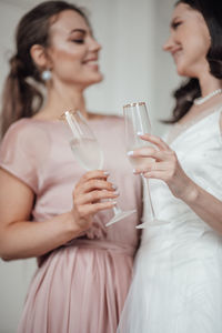 Bridesmaid and bride holding champagne flute