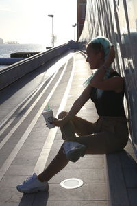 Side view of woman sitting on footpath