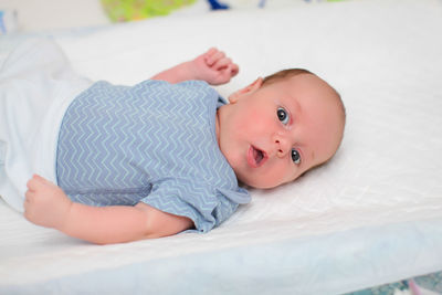 Portrait of cute baby lying on bed at home