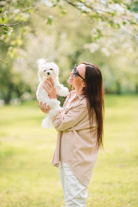 Woman with dog standing on field