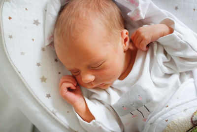 Newborn baby sleeps peacefully. gentle innocent baby lies on light baby cocoon, closeup 