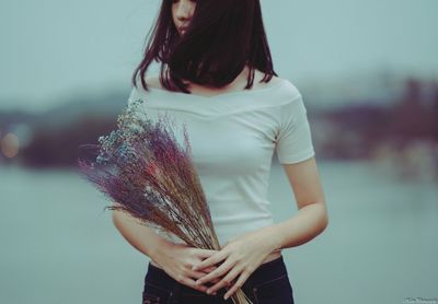 Midsection of woman holding umbrella while standing outdoors