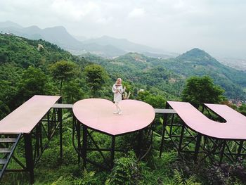 Woman standing on observation point against mountains