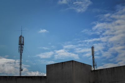 Low angle view of communication tower and building against sky