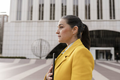 Businesswoman with tablet pc standing in front of building