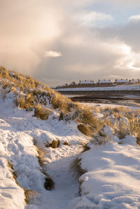 Scenic view of snow covered field against sky during sunset