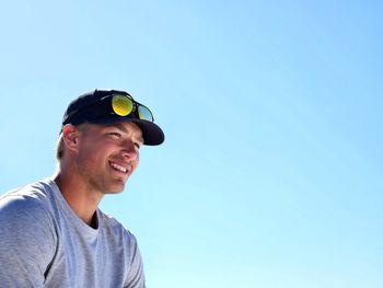 Low angle view of young man standing against blue sky