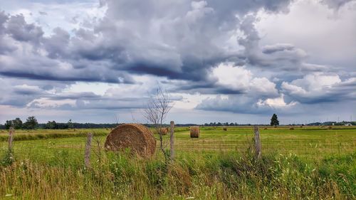 Hay bales on field against sky