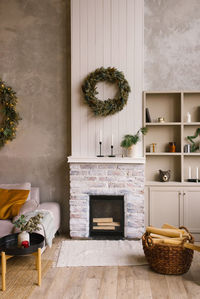 Interior of a country house with a fireplace, a christmas wreath, a wicker chair 