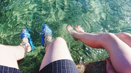 Low section of people in swimming pool against sea