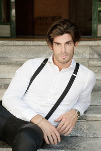 Portrait man wearing suspenders while sitting on steps