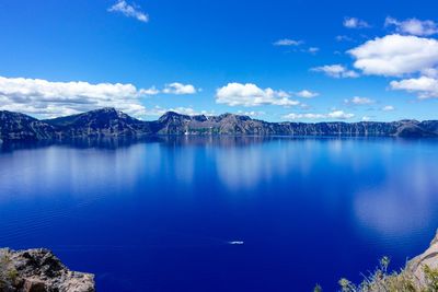 Scenic view of lake and mountains against blue sky