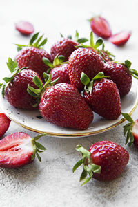 Fresh ripe delicious strawberries in a white plate on a gray stone background