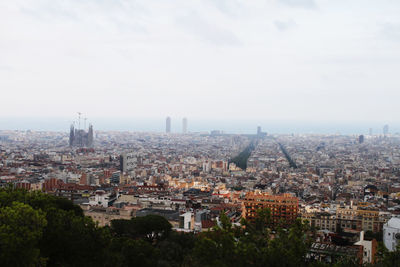 High angle view of city buildings against cloudy sky