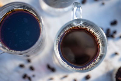 Glass mugs of black hot coffee, coffee beans, making coffee at home