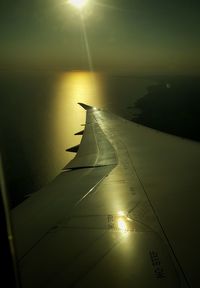 Close-up of airplane wing over lake during sunset