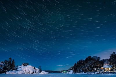 Scenic view of frozen lake against star trails at night