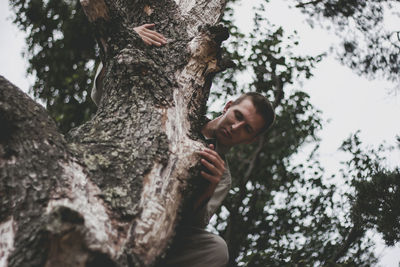 Low angle view of child on tree trunk
