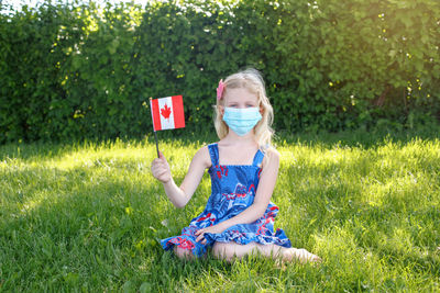 Caucasian girl in face protective mask holding waving canadian flag outdoor. canada day holiday 